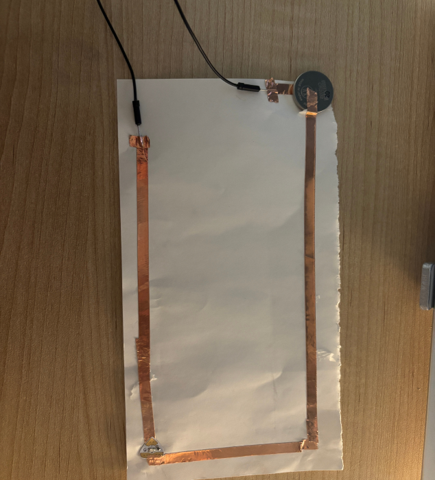 A paper circuit with external jumper wires connected.