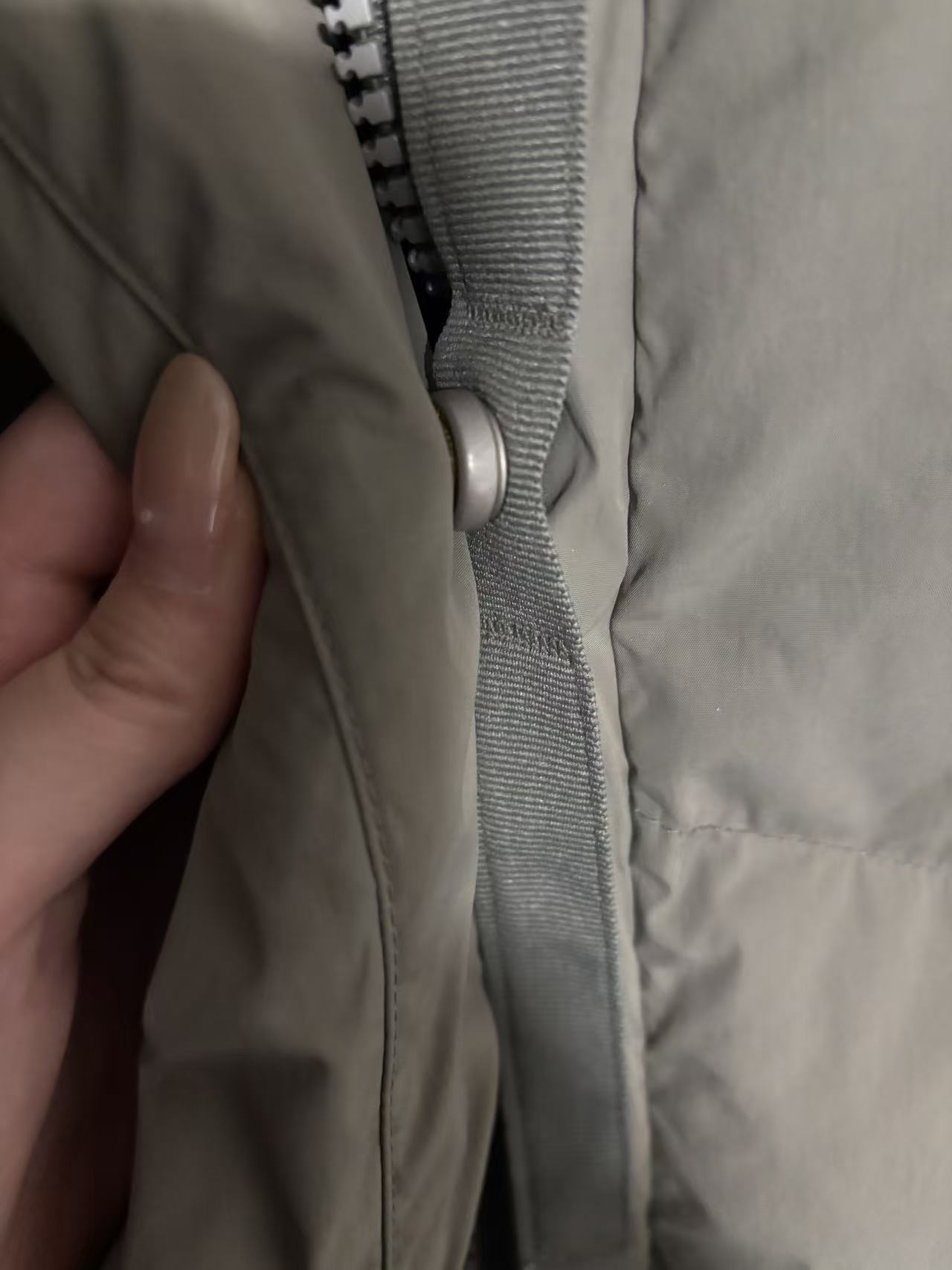 Fingers pulling a zipper on a jacket.