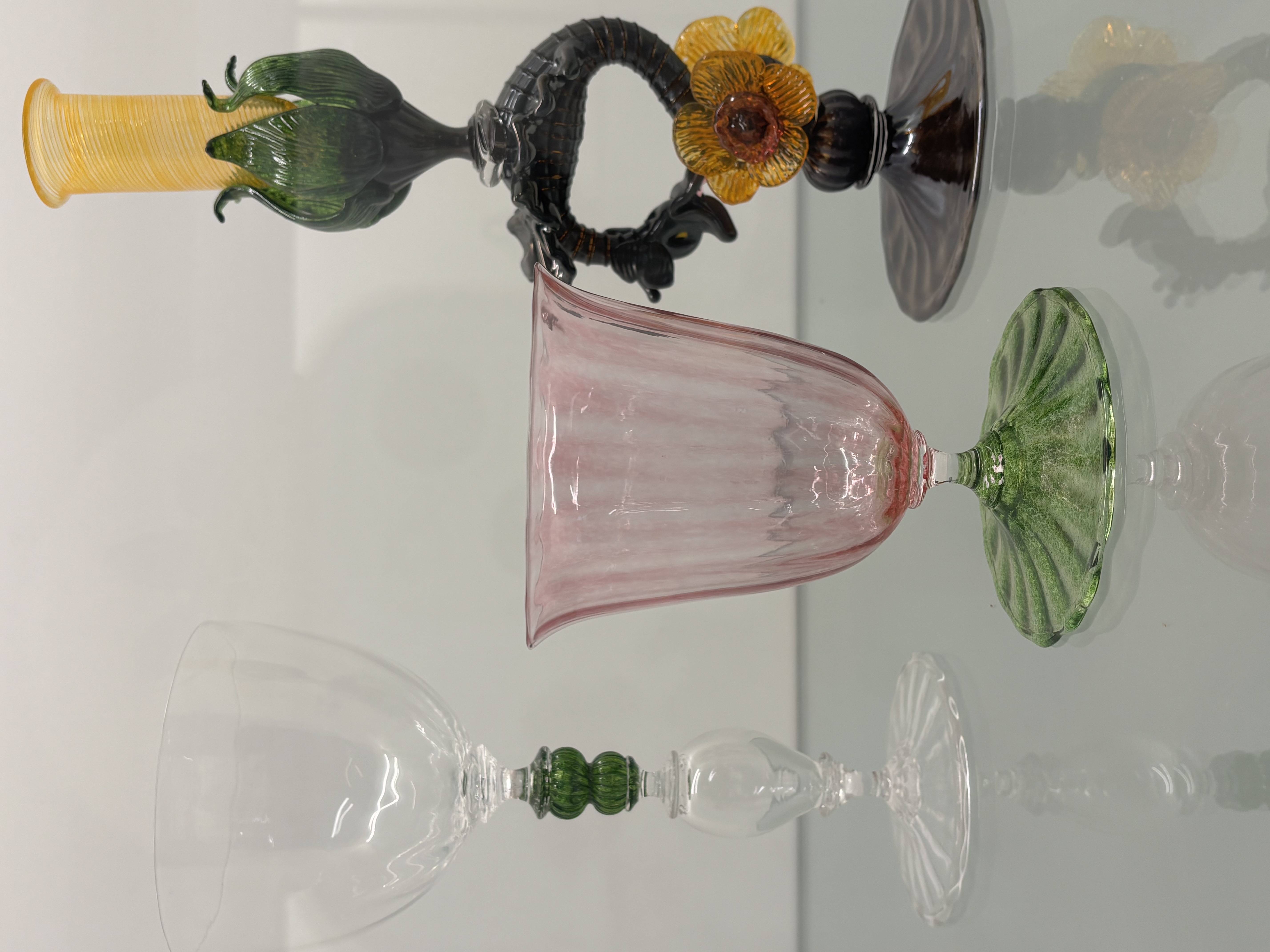 Three glass cups made from molten glass on the display stand. <div class='container'><iframe class='responsive-iframe' src='https://www.youtube.com/embed/tgbNymZ7vqY'></iframe></div>