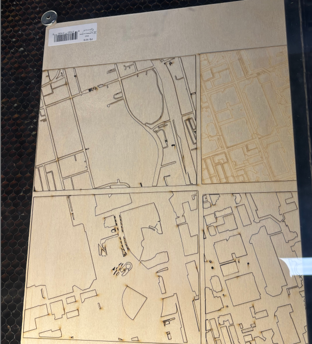  The image displays the completed laser-cut wooden map, featuring layered structures like buildings and roads.
